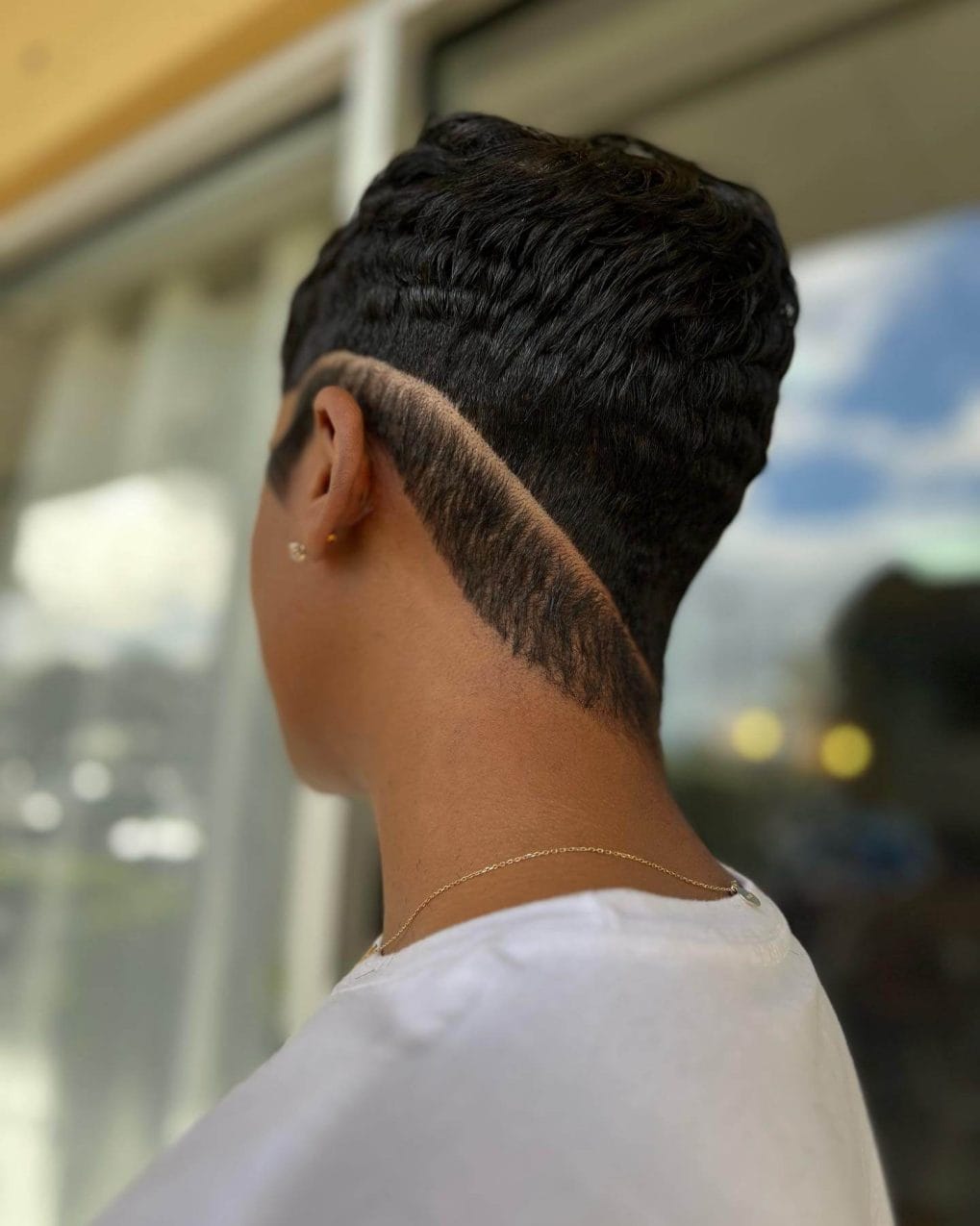 Glossy, textured black waves over a sharply defined, skin-fade undercut.
