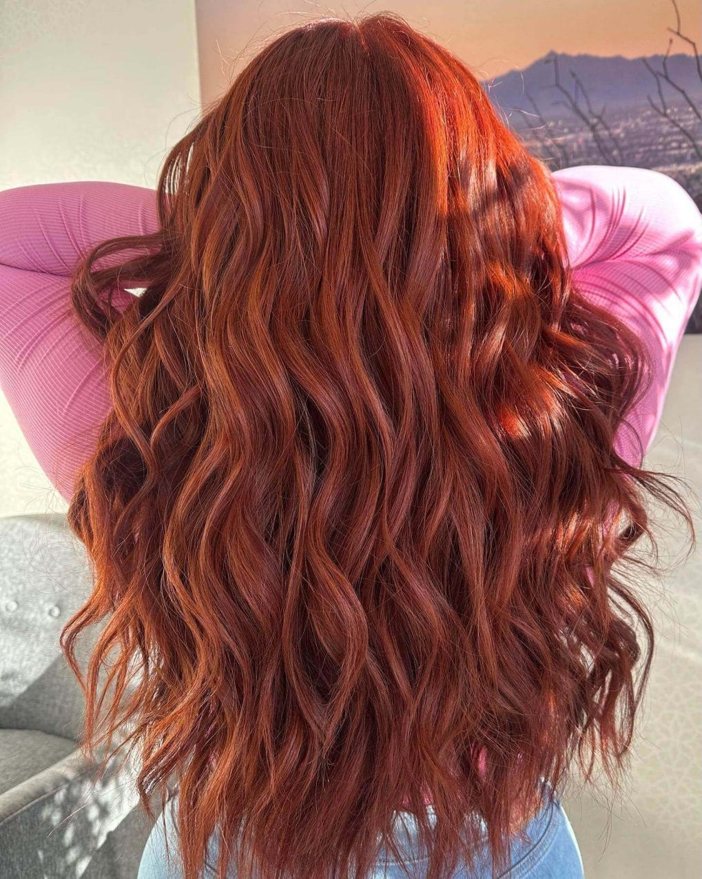 Glossy copper hair with voluminous curls and long, bouncing layers.