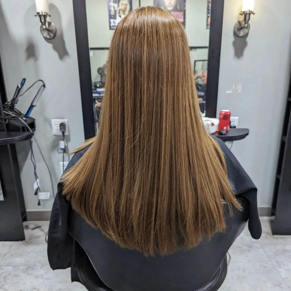 Golden-brown sleek U-shaped haircut cascading effortlessly with subtle highlights.

