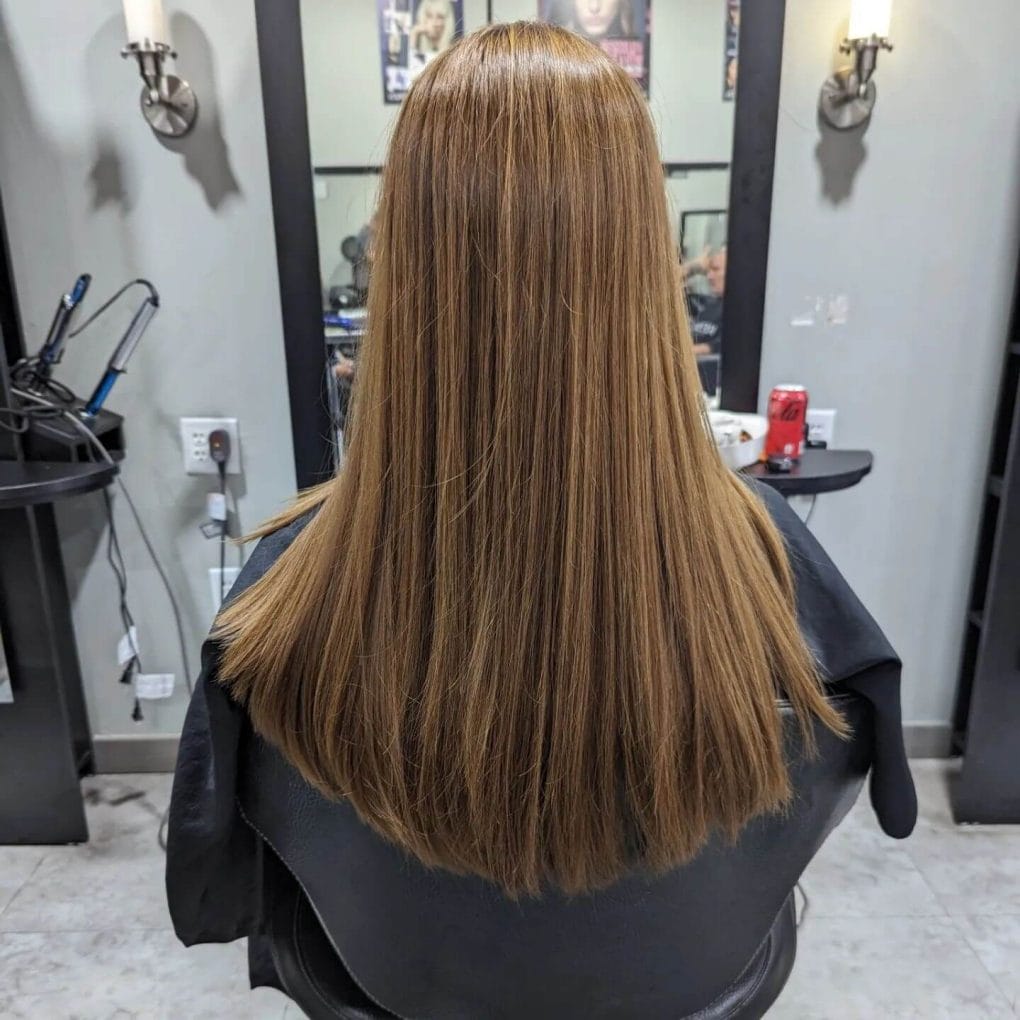 Golden-brown sleek U-shaped haircut cascading effortlessly with subtle highlights.