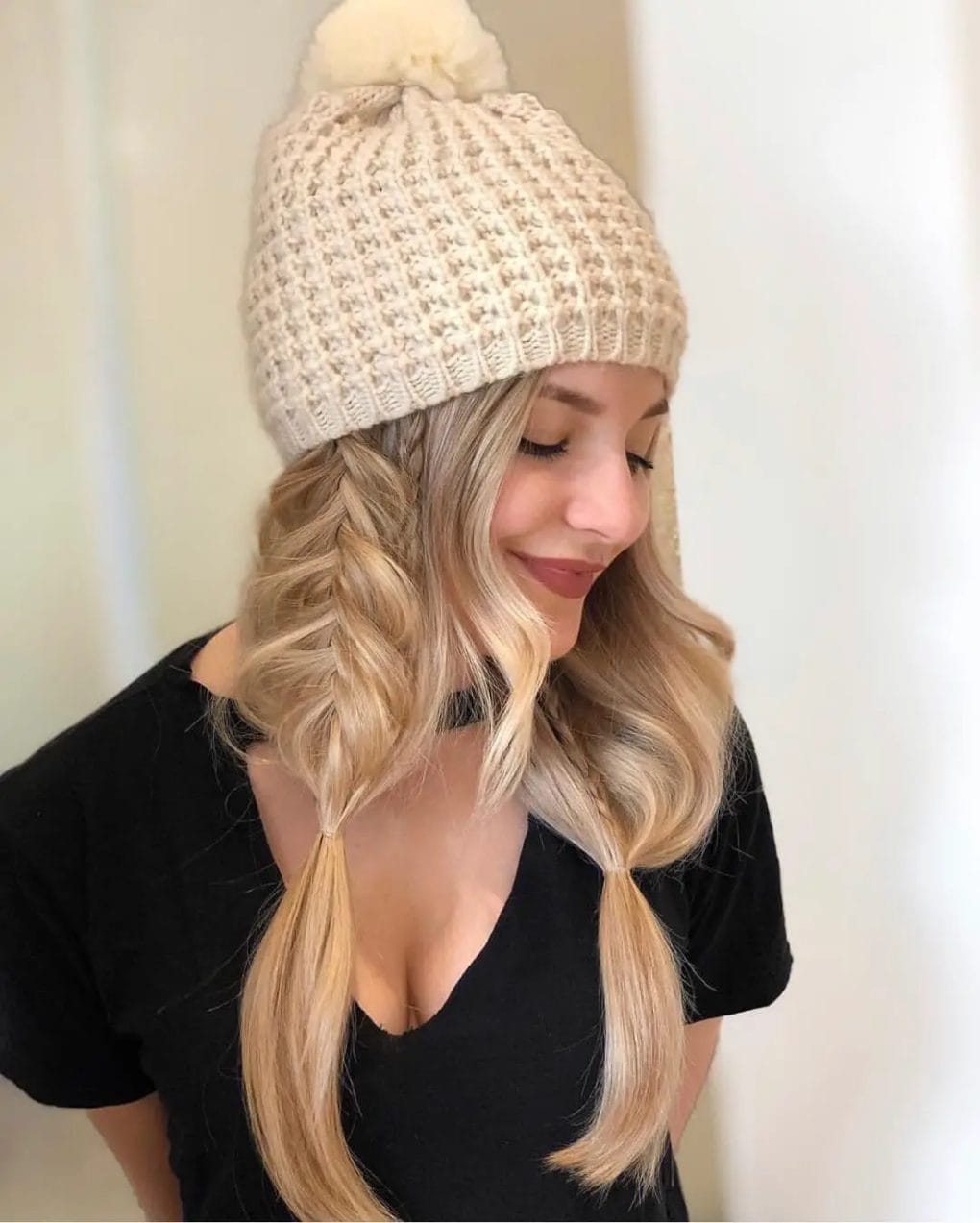 Golden blonde waves enhanced by a chunky knit creamy beanie with pompom.