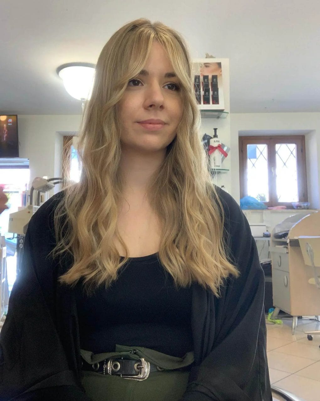 Lustrous golden blonde waves with seamlessly blended curtain bangs, adding volume and depth.