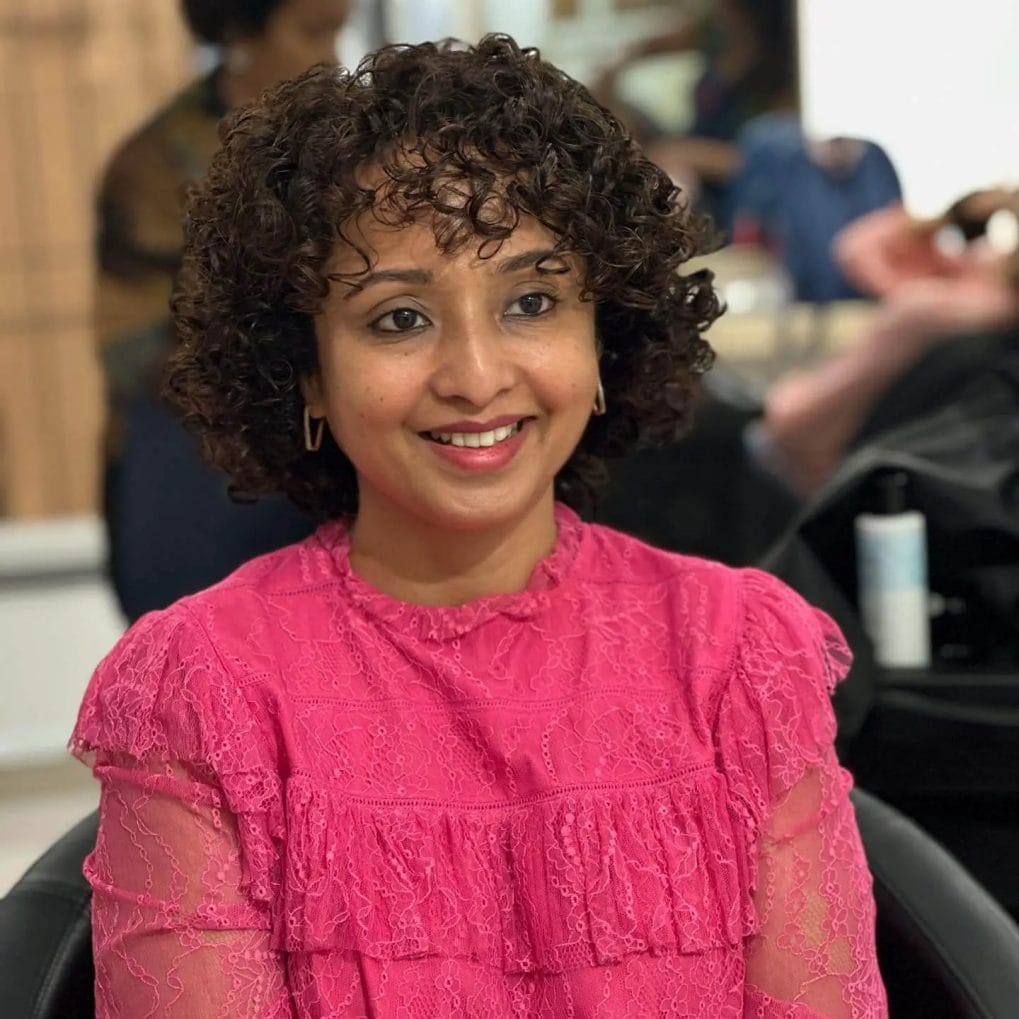 Short, bouncy perm with medium-sized curls framing the face.