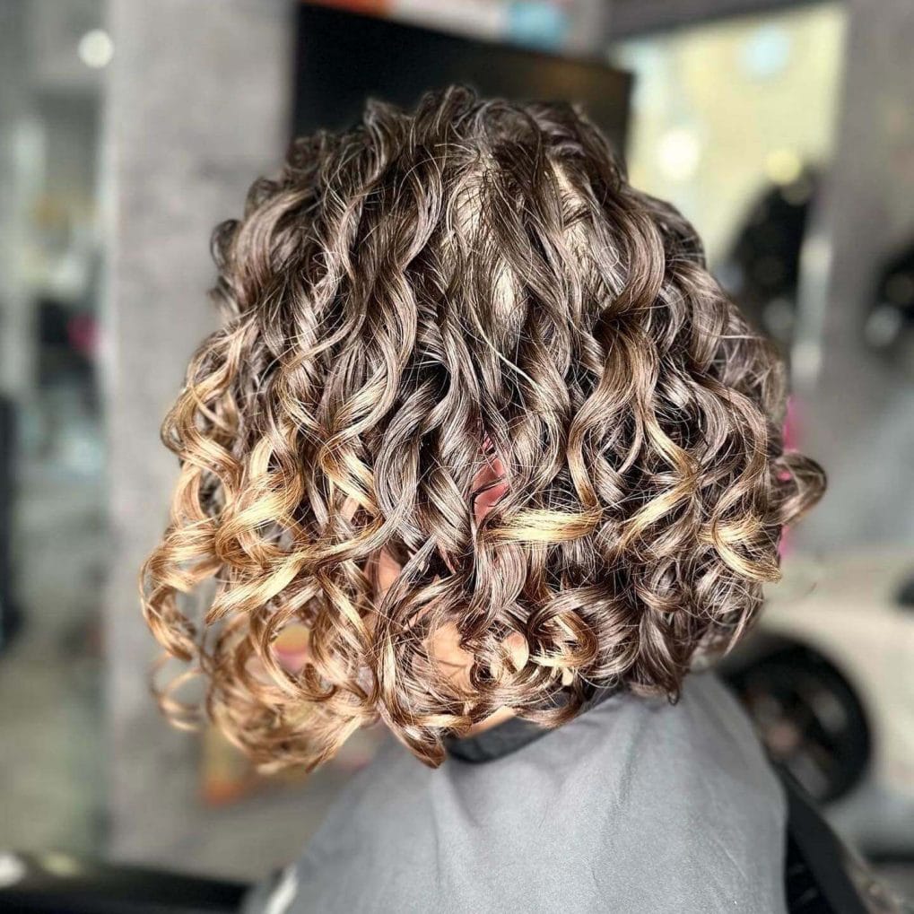 Gradient A-line bob with stacked curls and warm colors.