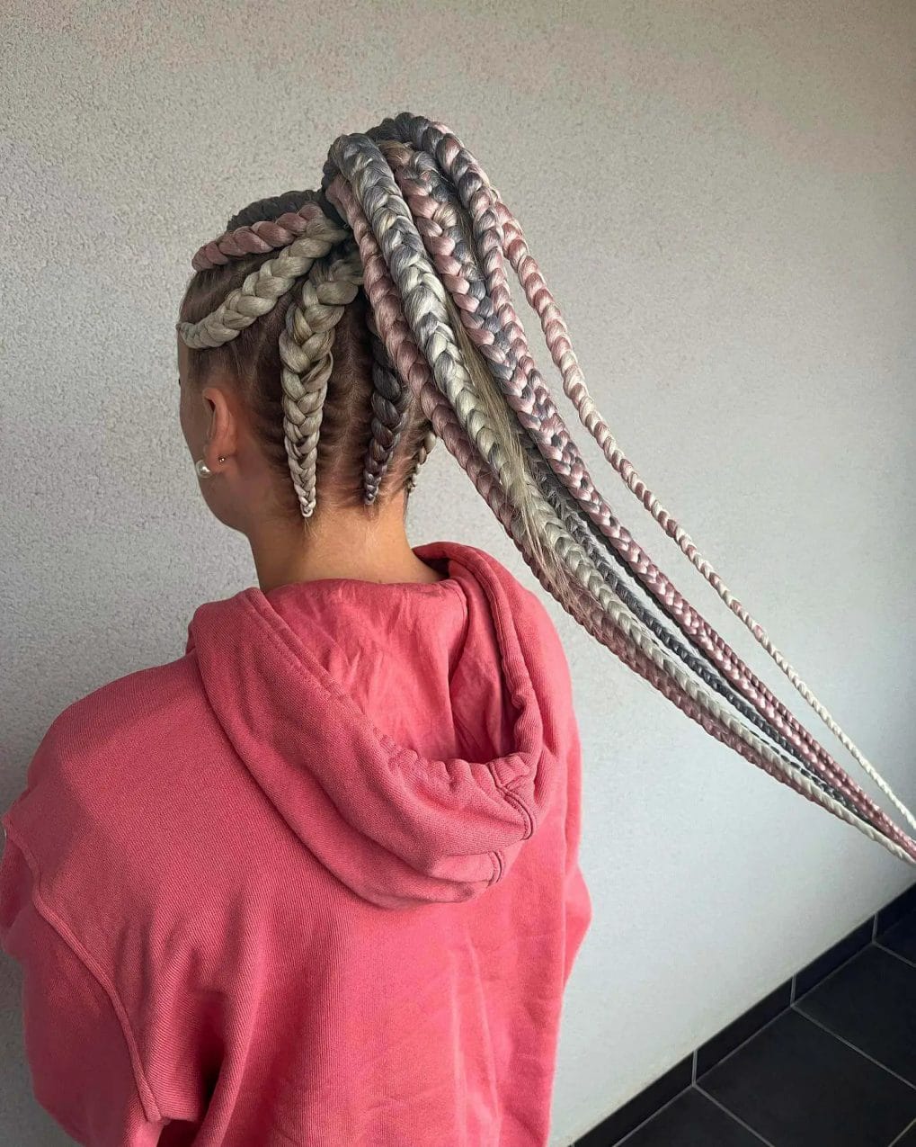 Multiple long braids in silvery grey and pastel pink as a ponytail, intricately woven.