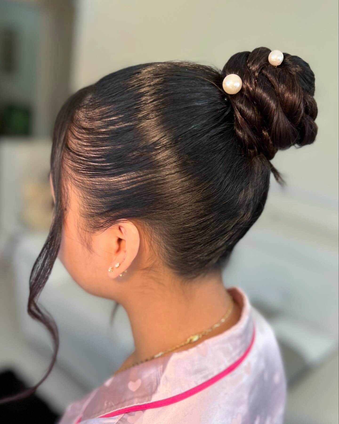 High braided bun with pearl pins and a loose curl.