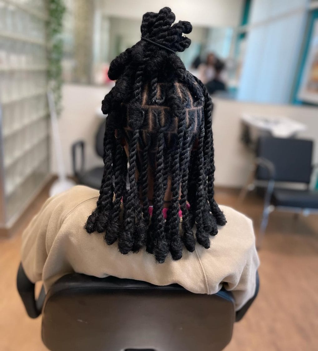 Long black kinky twists in a high ponytail accented with pink rubber bands