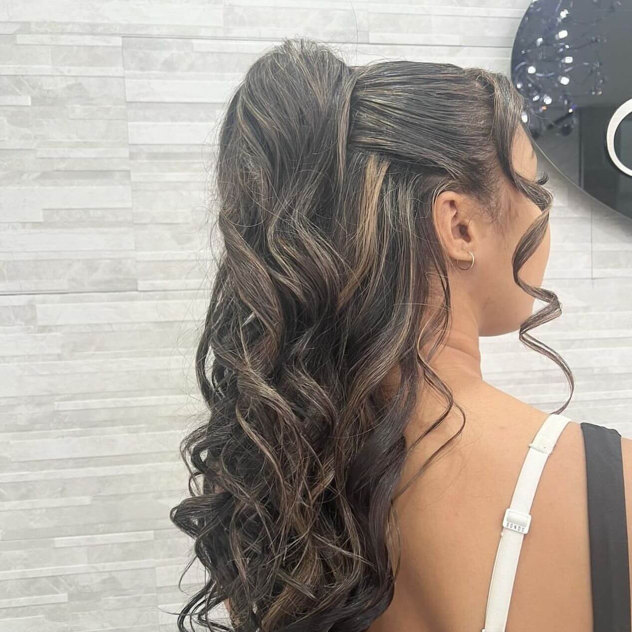 High ponytail with voluminous caramel curls.