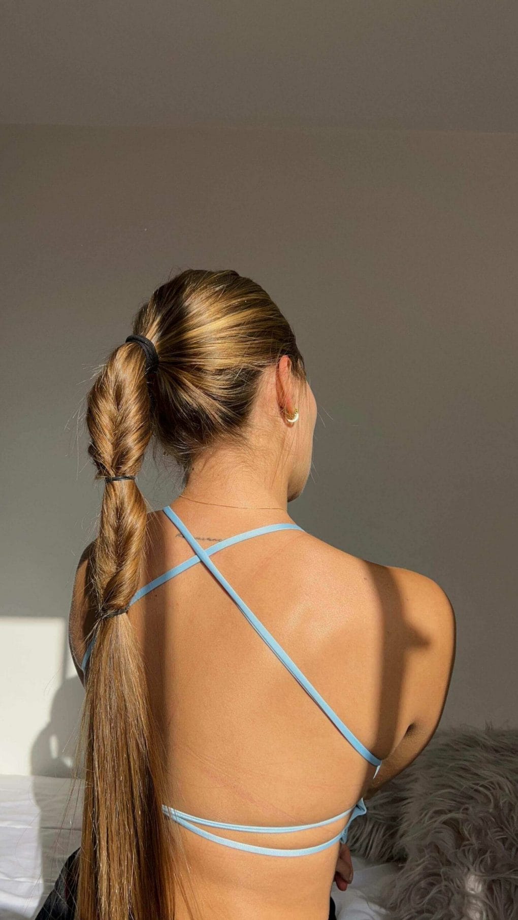 High ponytail transitioning into a honey-blonde twisted braid suitable for softball
