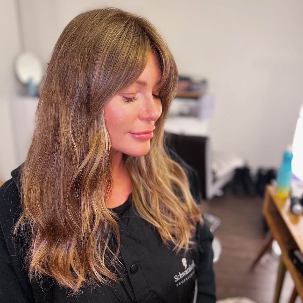 Transition from bardot bangs to sun-kissed highlighted long layers, epitomizing a balance between classic and modern.