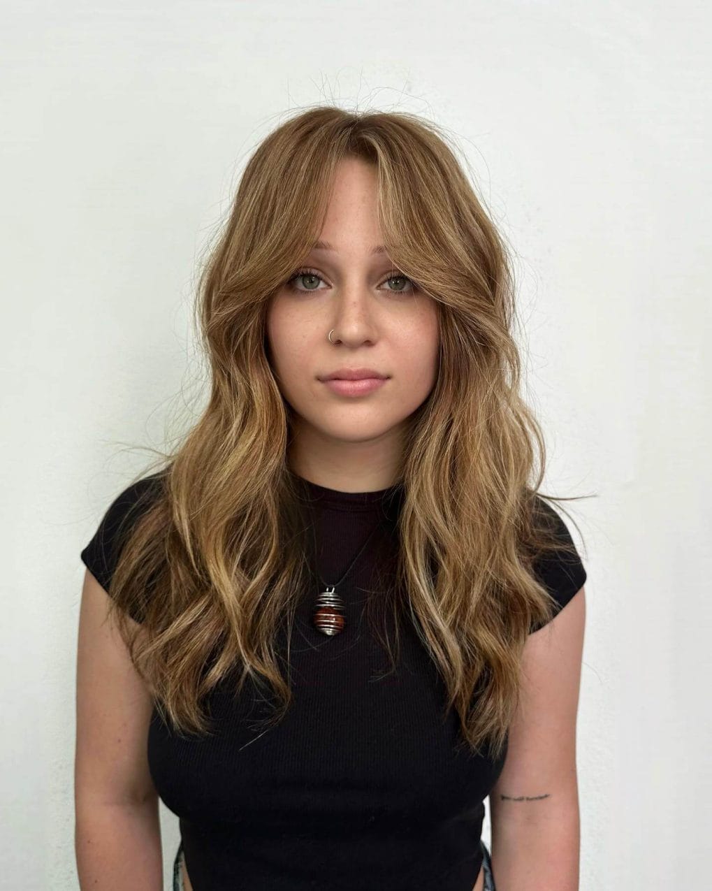 Laid-back honey blonde beach waves with long wispy bangs.