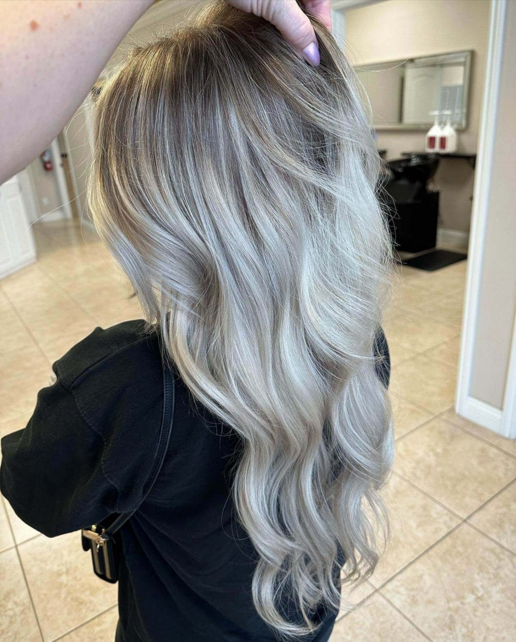Icy blonde balayage from dark roots to silver ends, portraying winter's crisp elegance.