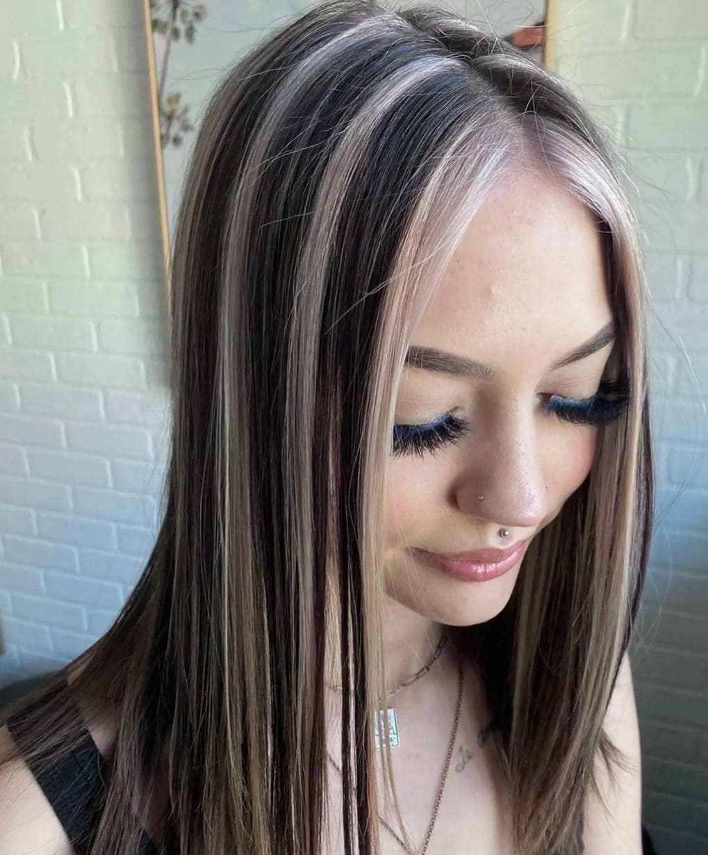 Icy blonde highlights in straight, chest-length brunette, off-center parting.