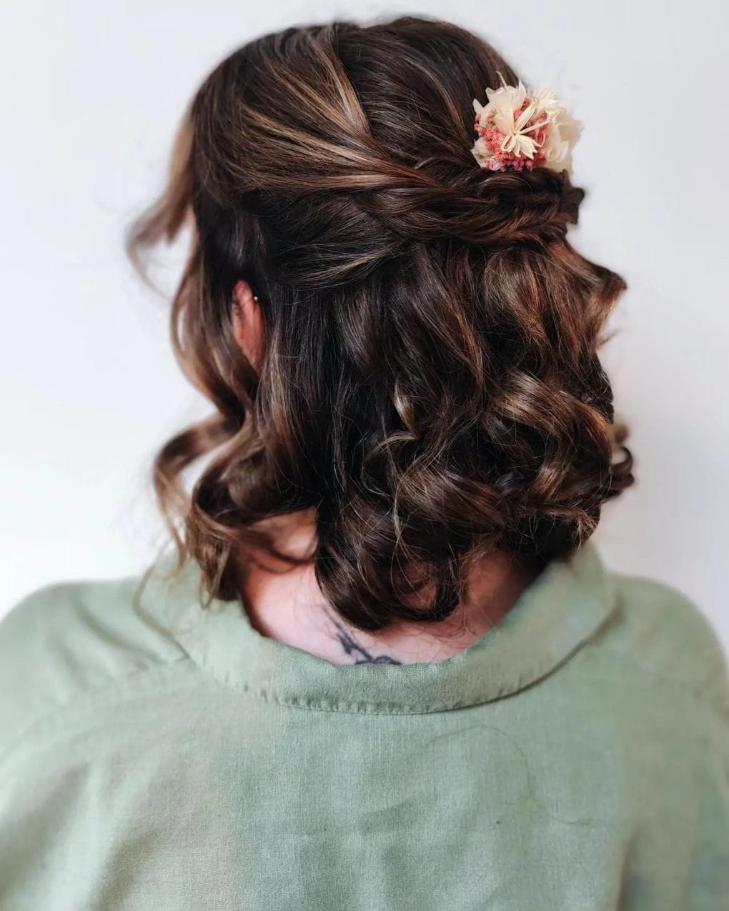 Rich chocolate curls in an intricate side-swept updo with a floral accessory for a birthday soirée.