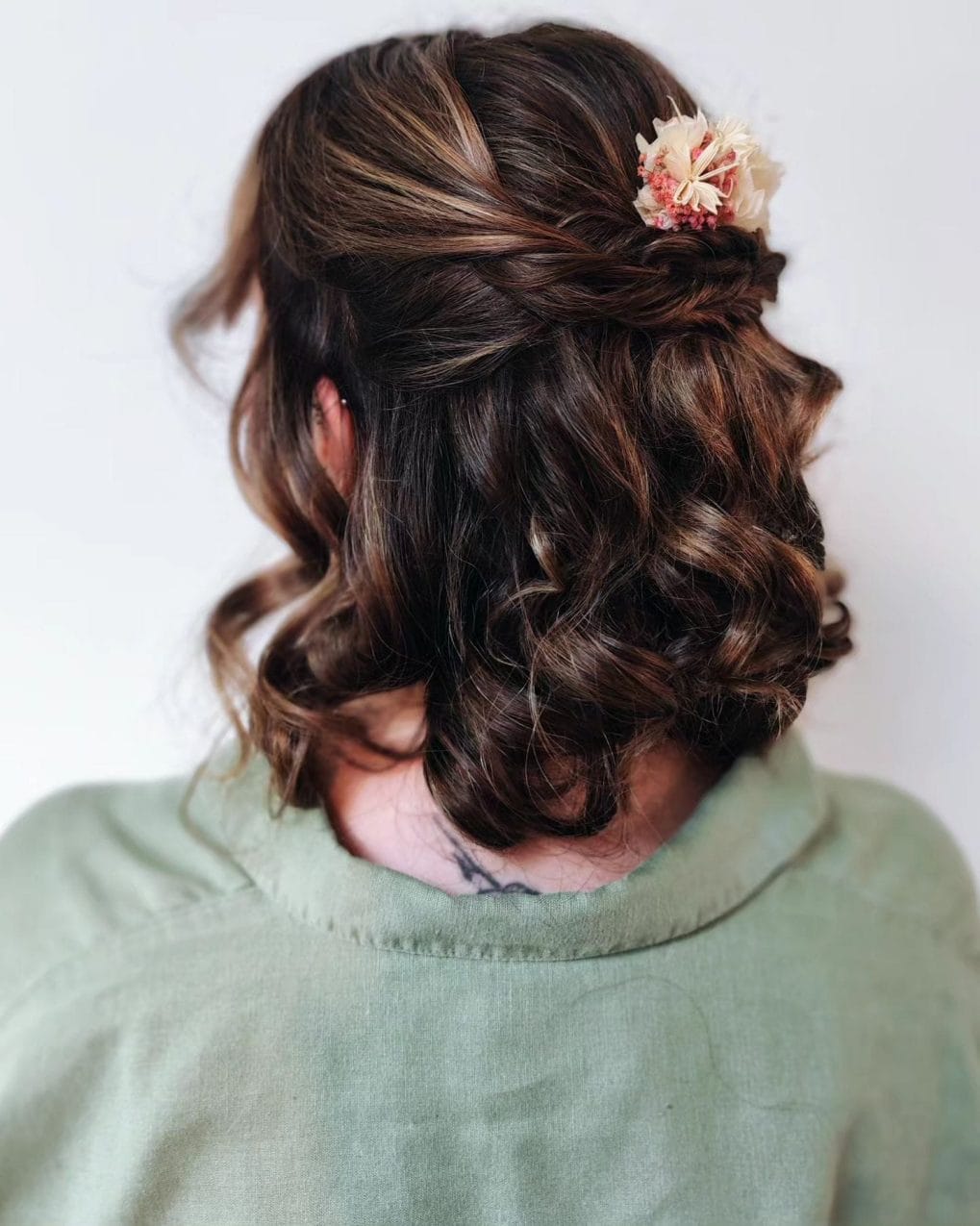 Rich chocolate curls in an intricate side-swept updo with a floral accessory for a birthday soirÃ©e.