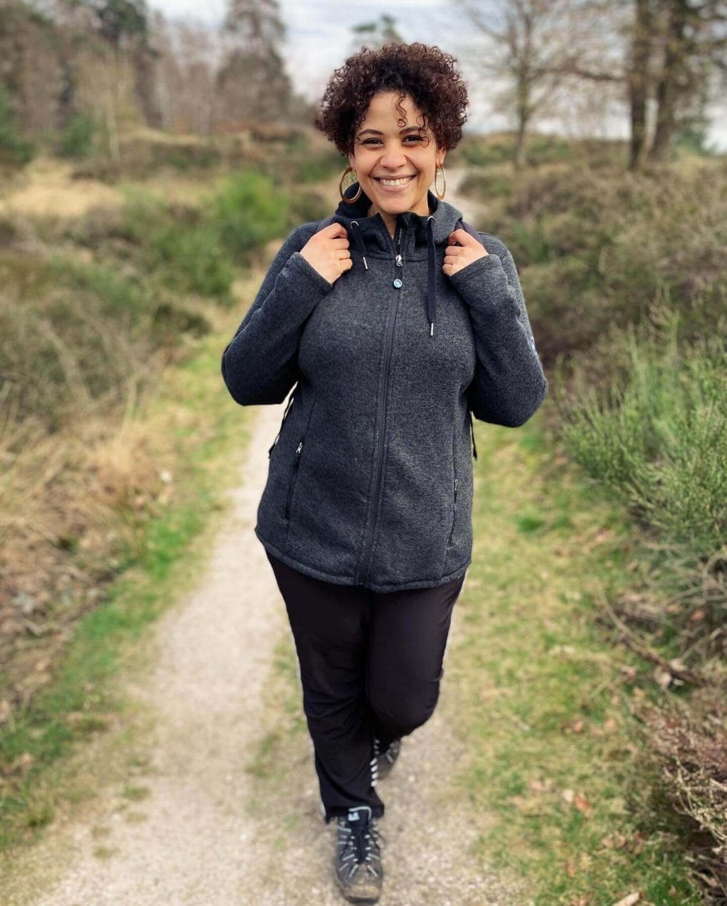 Hiker with joyful tight ringlets exuding a carefree spirit on trail