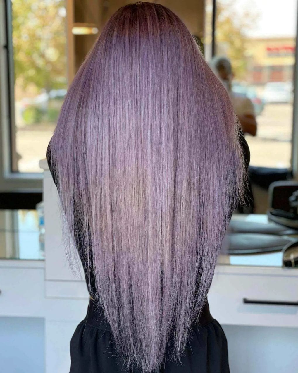 Vivid lavender to silver balayage on straight, long layered hair.