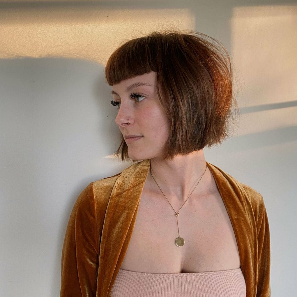Layered auburn bob with razor-cut edges and straight bangs