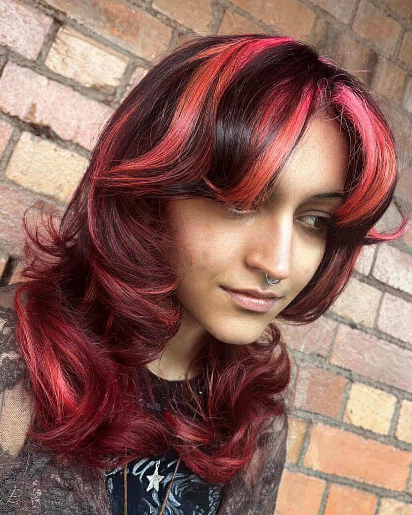 Layered medium hair with red and dark chunky highlights and curtain bangs