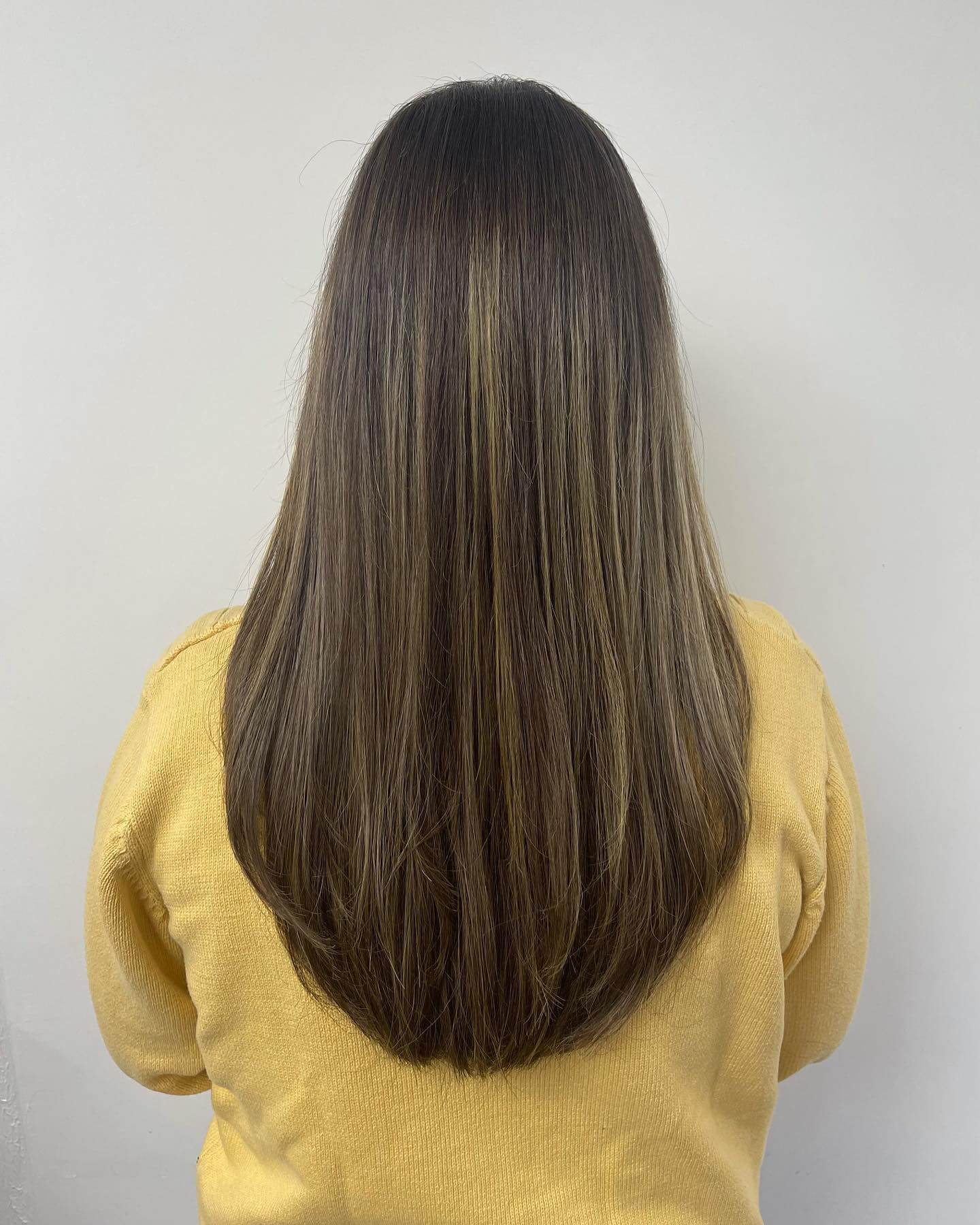 Subtle layered U-shaped hair with sun-kissed highlights and gentle curve.