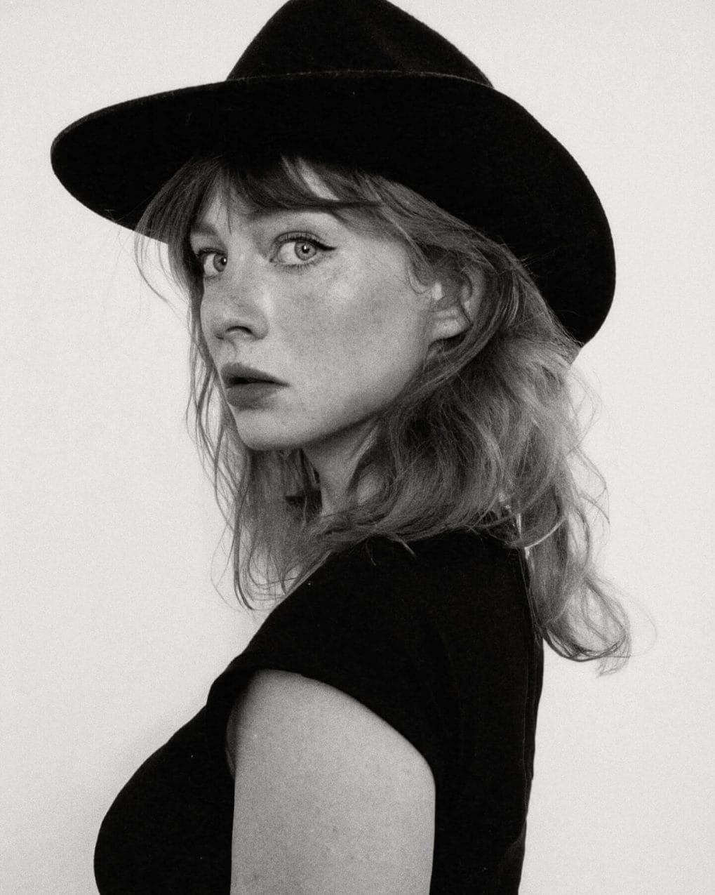 Light wavy hair tossed to one side under a hat, embracing the wind