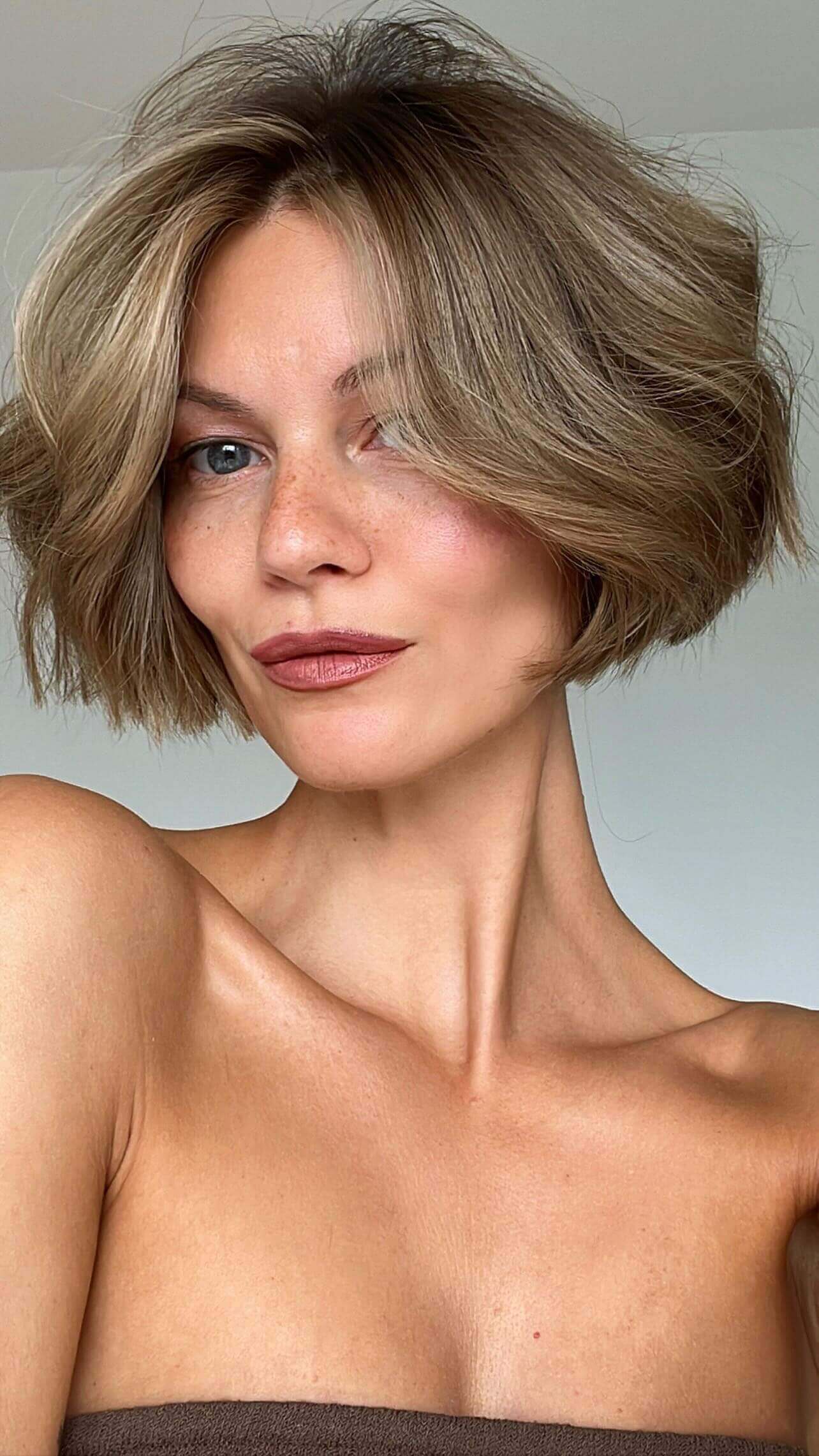 Lively '90s bob with tousled layers, sun-kissed highlights, and shorter back