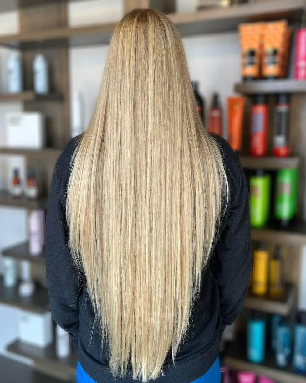 Extended blond locks with defined V-cut layers for volume and flow.