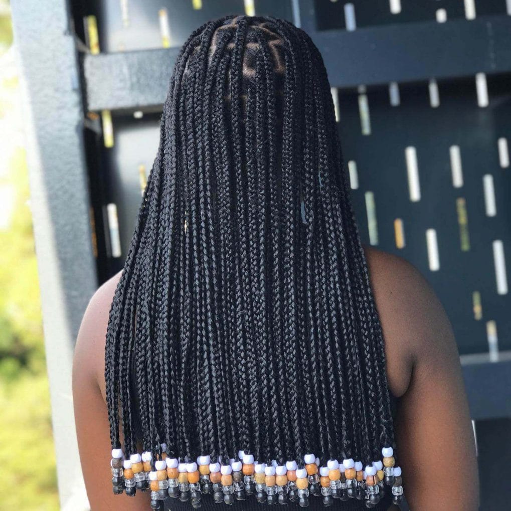 Long, slender black box braids with orange, white, and dark beads at ends.