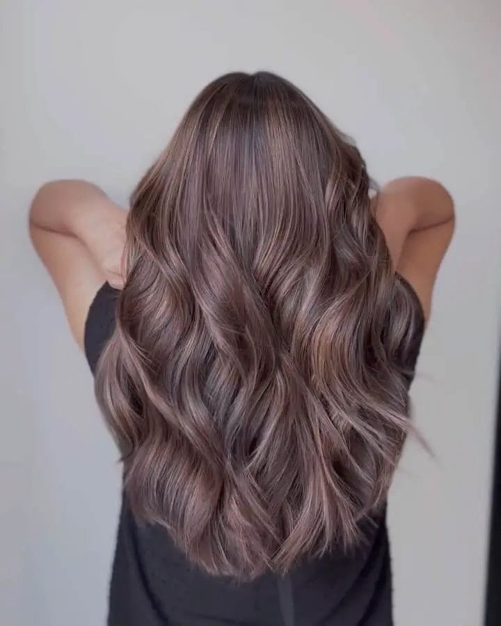 Long cascading waves in cool ash and lilac tones on hair.