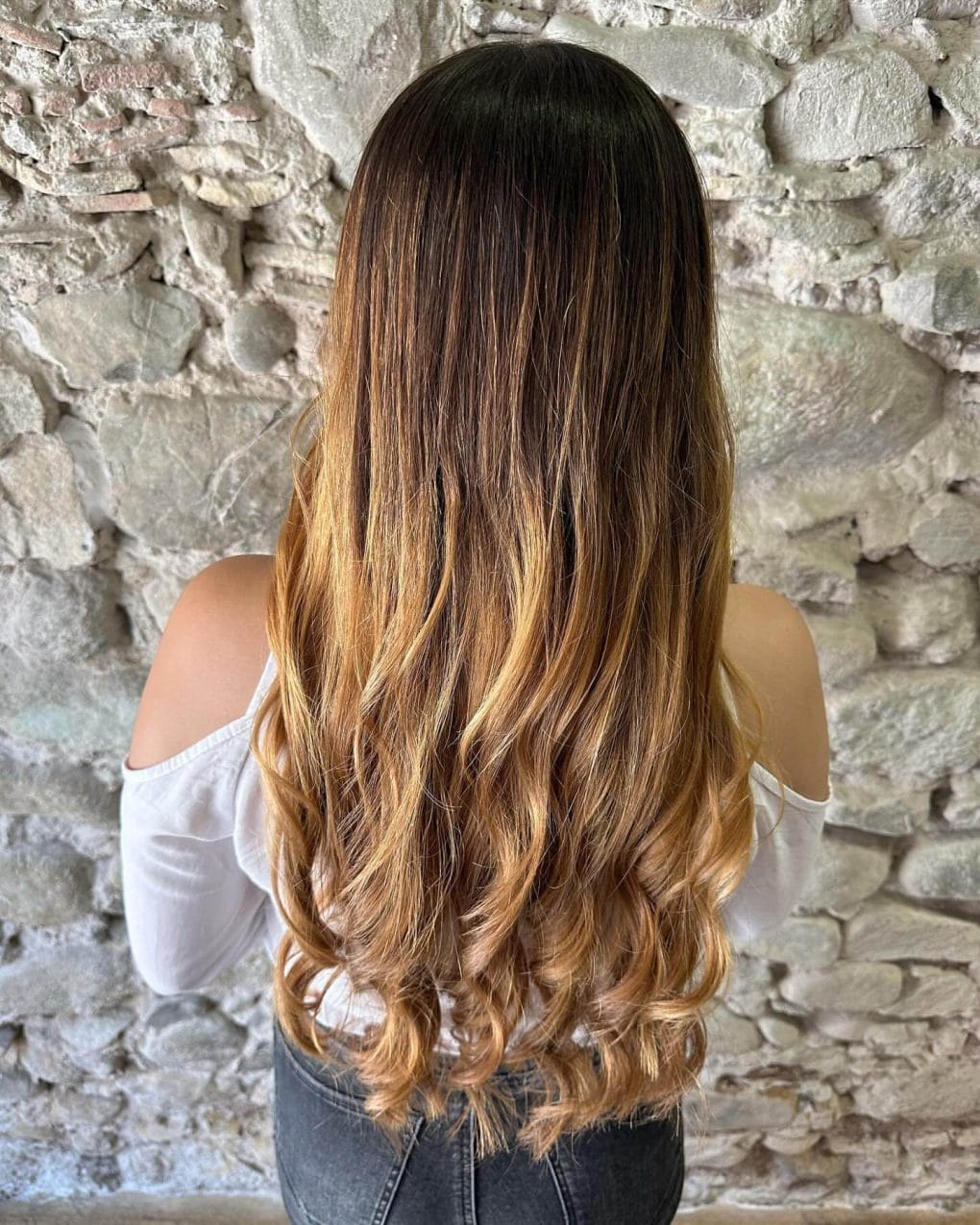 Long flowing curls with dark roots and golden balayage