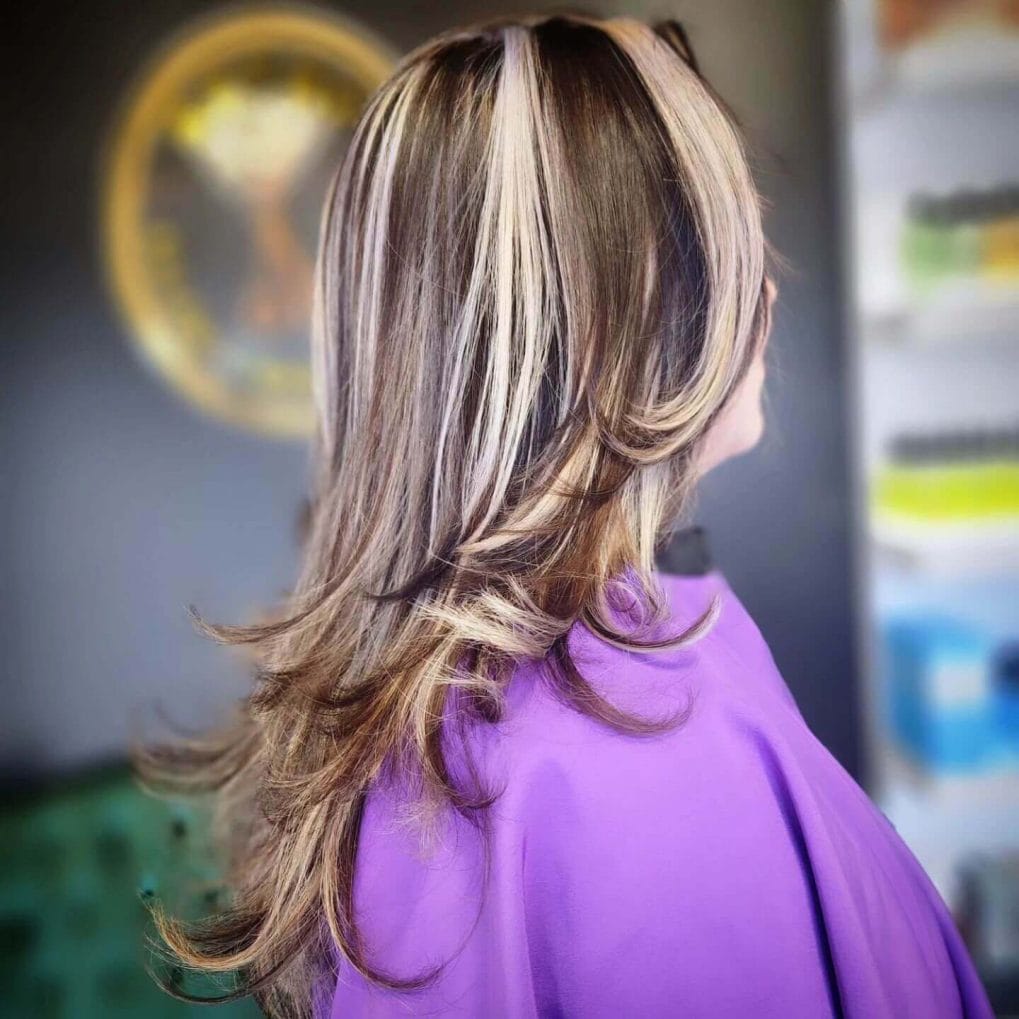 Long layered hair with blonde and light brown chunky highlights adding sophistication
