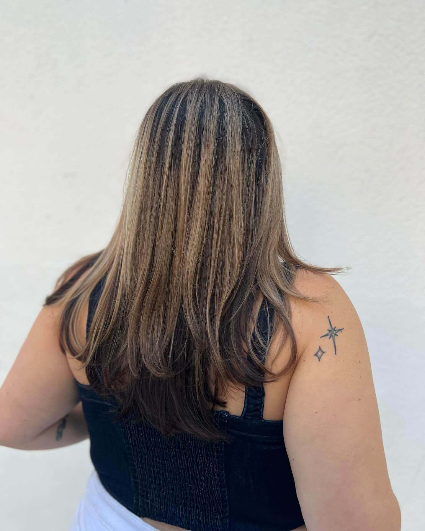 Long straight hair with blonde and brown chunky highlights for a sleek look