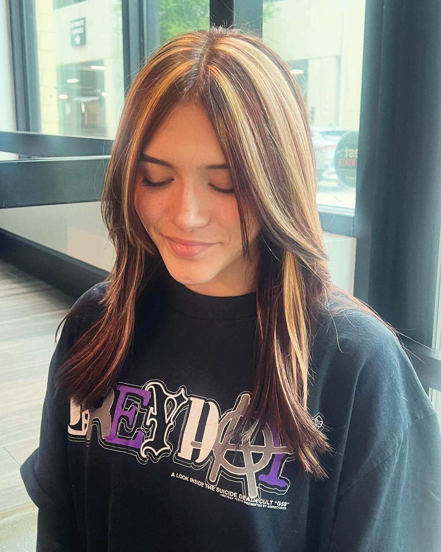 Long straight hair with blonde and dark brown chunky highlights and curtain bangs