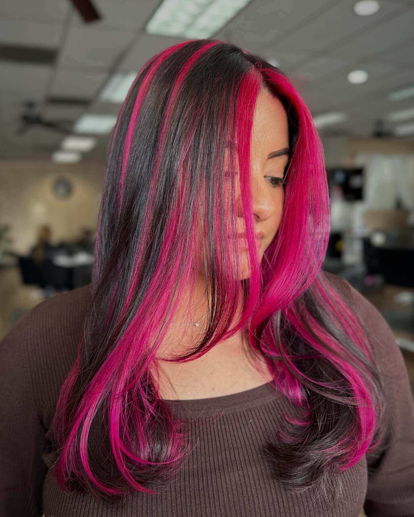 Long straight hair with pink and black chunky highlights for a striking style