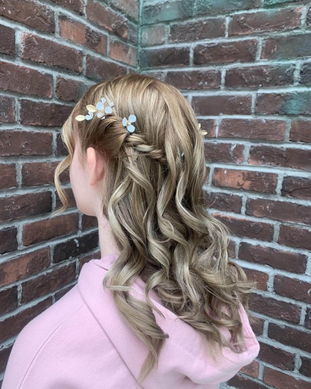 Long wavy blonde hair with a delicate braid and floral accessories
