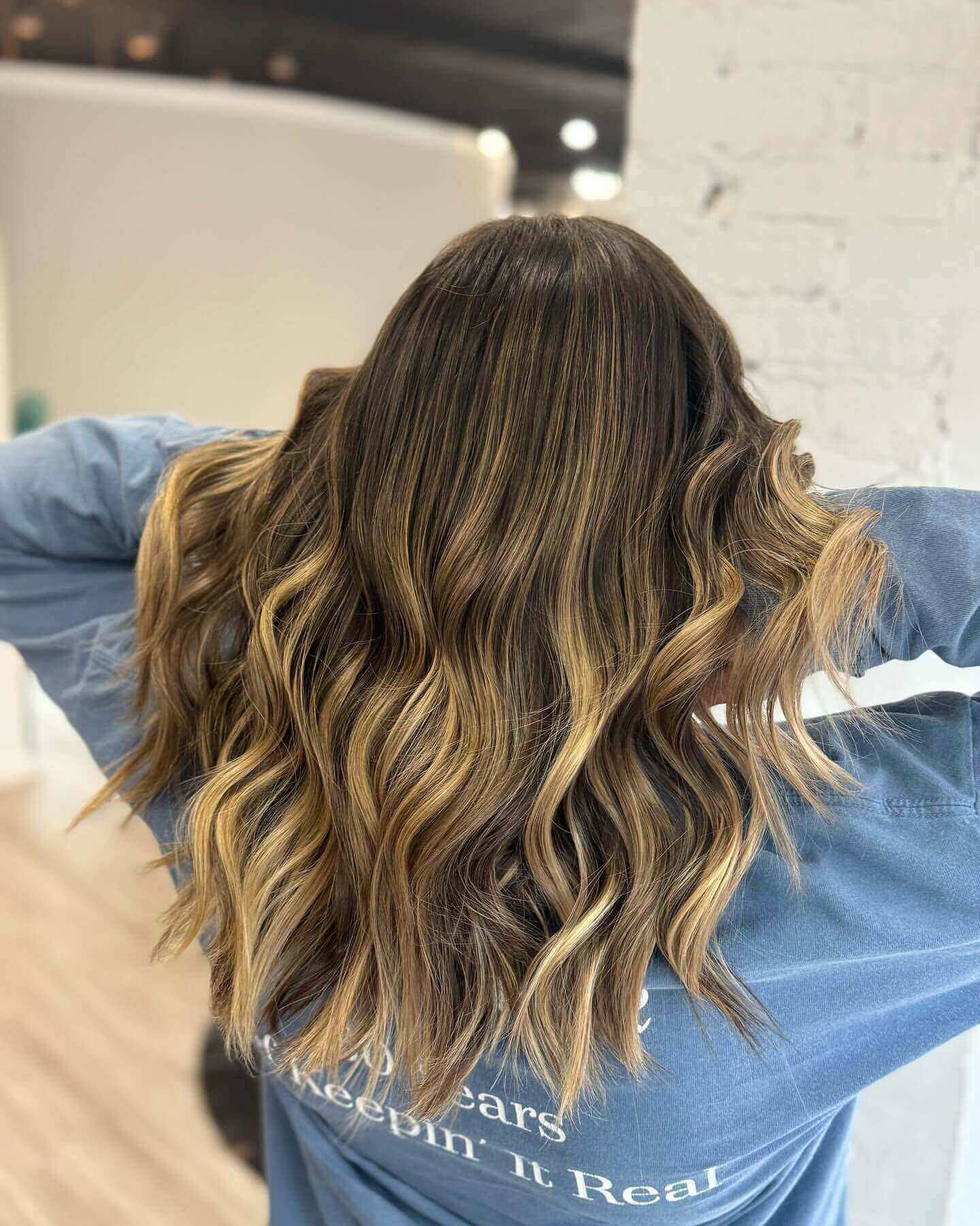 Long wavy hair with blonde and light brown chunky highlights adding volume