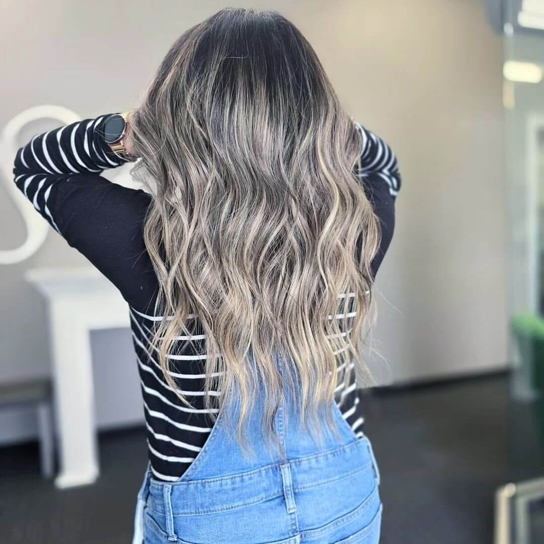 Long wavy layers with dark roots and ash blonde balayage
