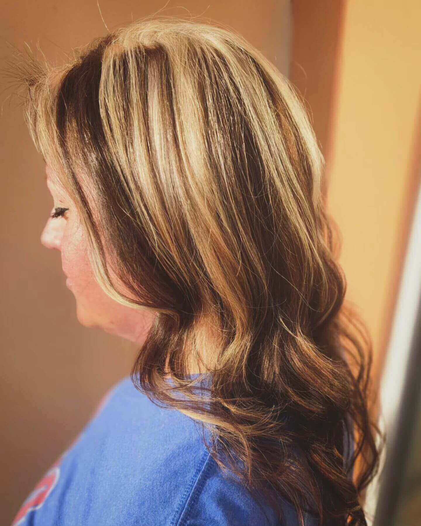 Long wavy hair with golden blonde and light brown chunky highlights for a warm look
