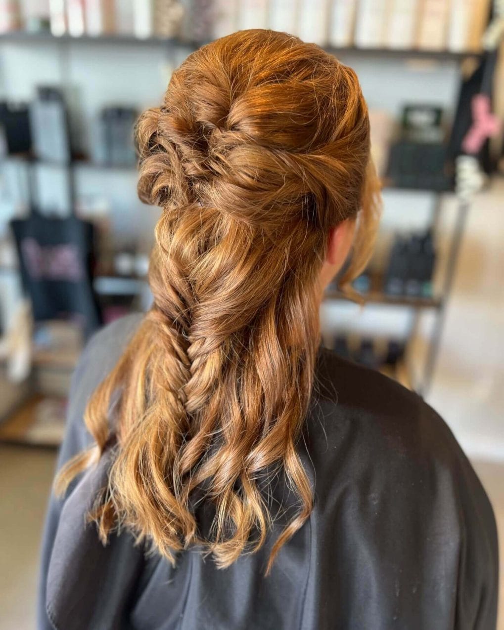 Half-up fishtail braid with long wavy hair.