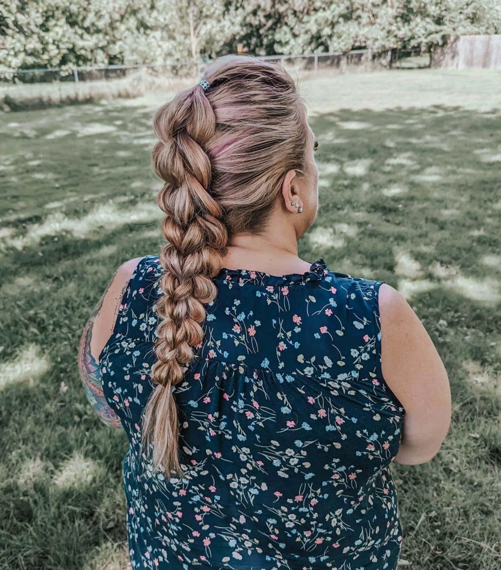 Loosely braided ponytail with pink and blonde hues for a soft, sun-kissed look.