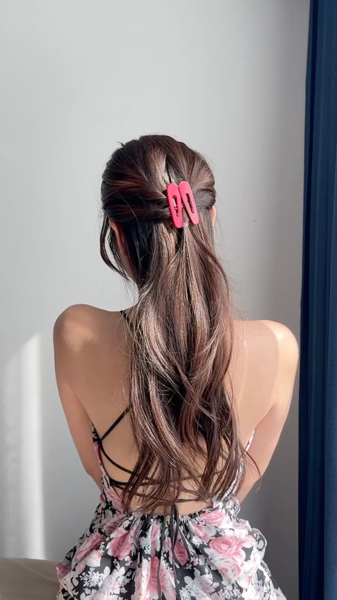 Long, loose ponytail with a bright pink clip, fun and practical for active wear