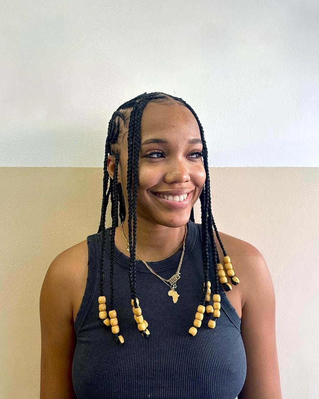 Medium-length chunky box braids with golden beads, framing the face.
