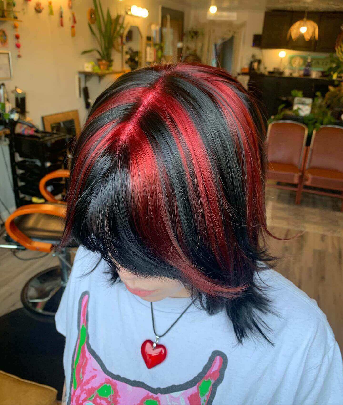 Medium choppy layered hair with red and black chunky highlights and bangs