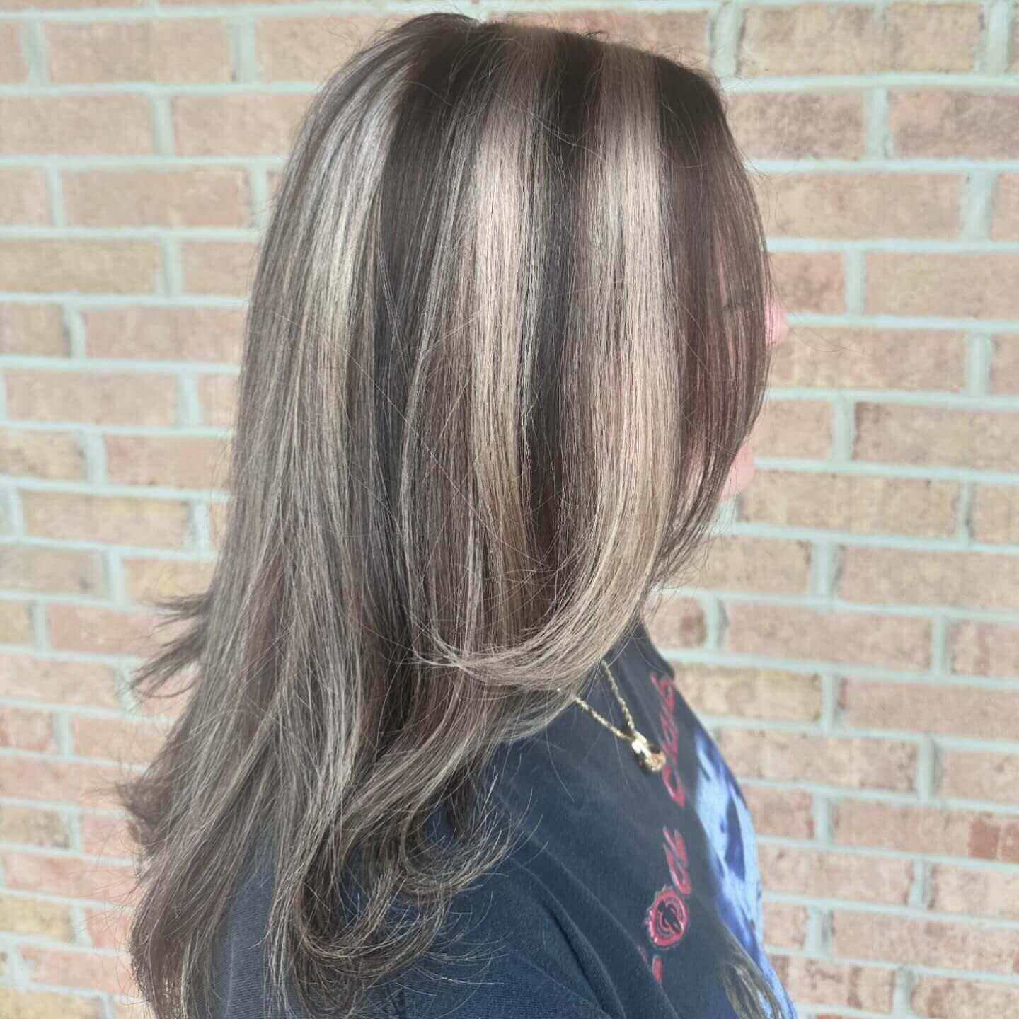Medium straight hair with blonde and dark brown chunky highlights adding elegance