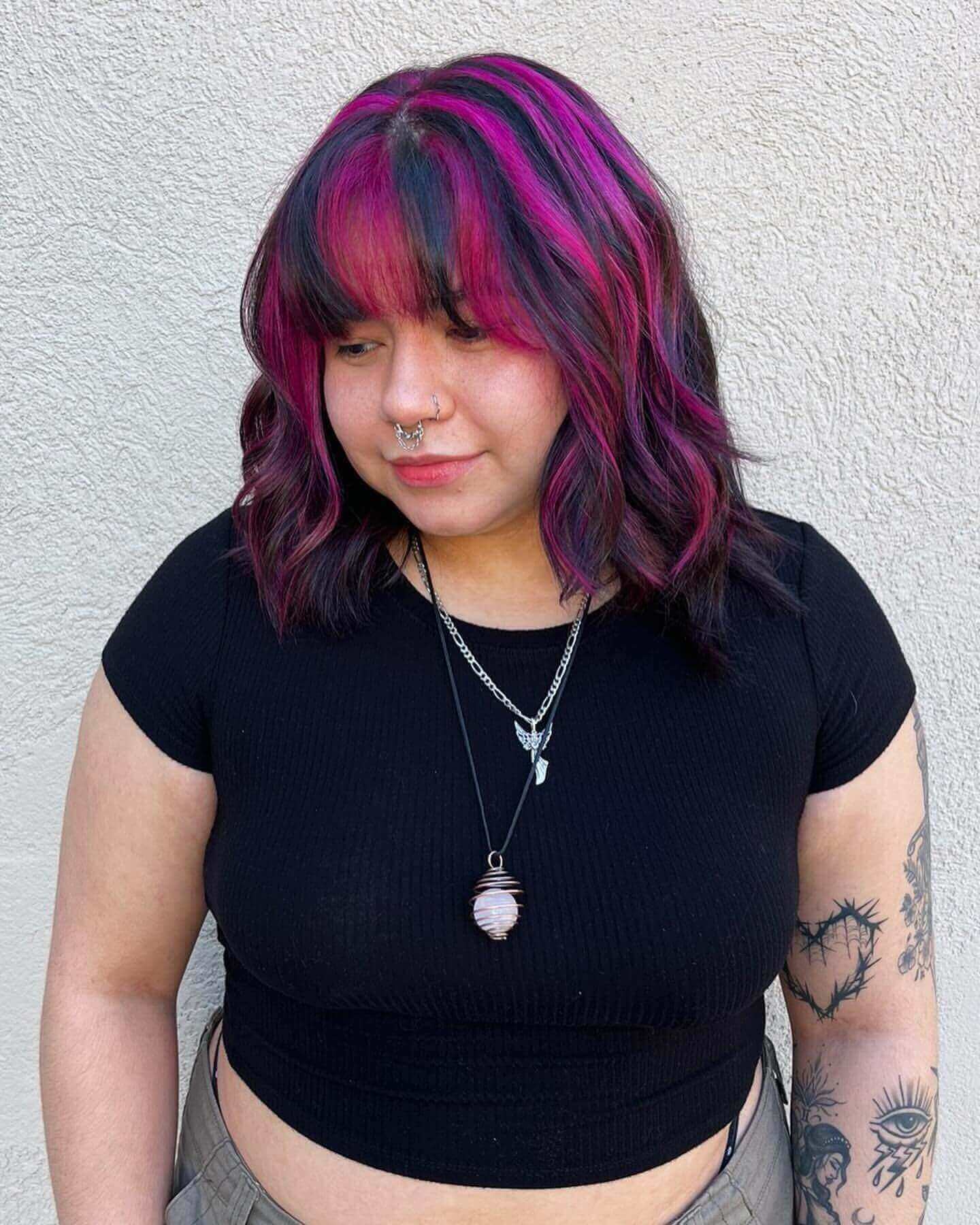 Medium wavy hair with pink and purple chunky highlights and curtain bangs