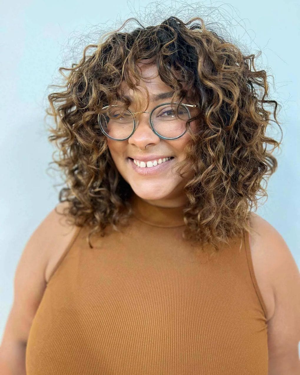 Mid-length cut with cascading brown curls and playful bangs.
