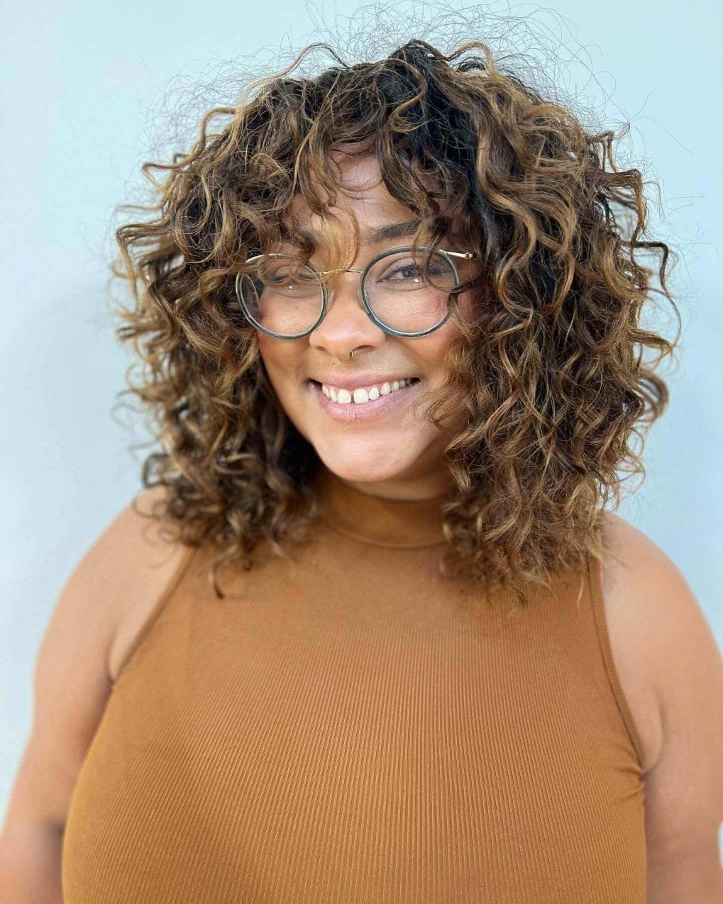 Mid-length cut with cascading brown curls and playful bangs.