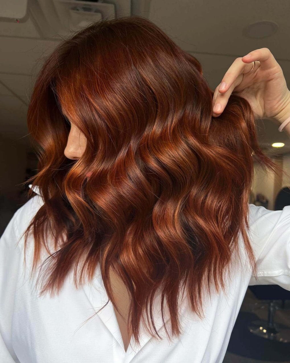 Mid-length copper hair with natural curl and subtly crafted layers.