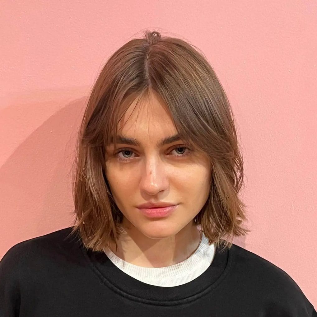 Minimalist straight jaw-length bob with soft brown curtain bangs.