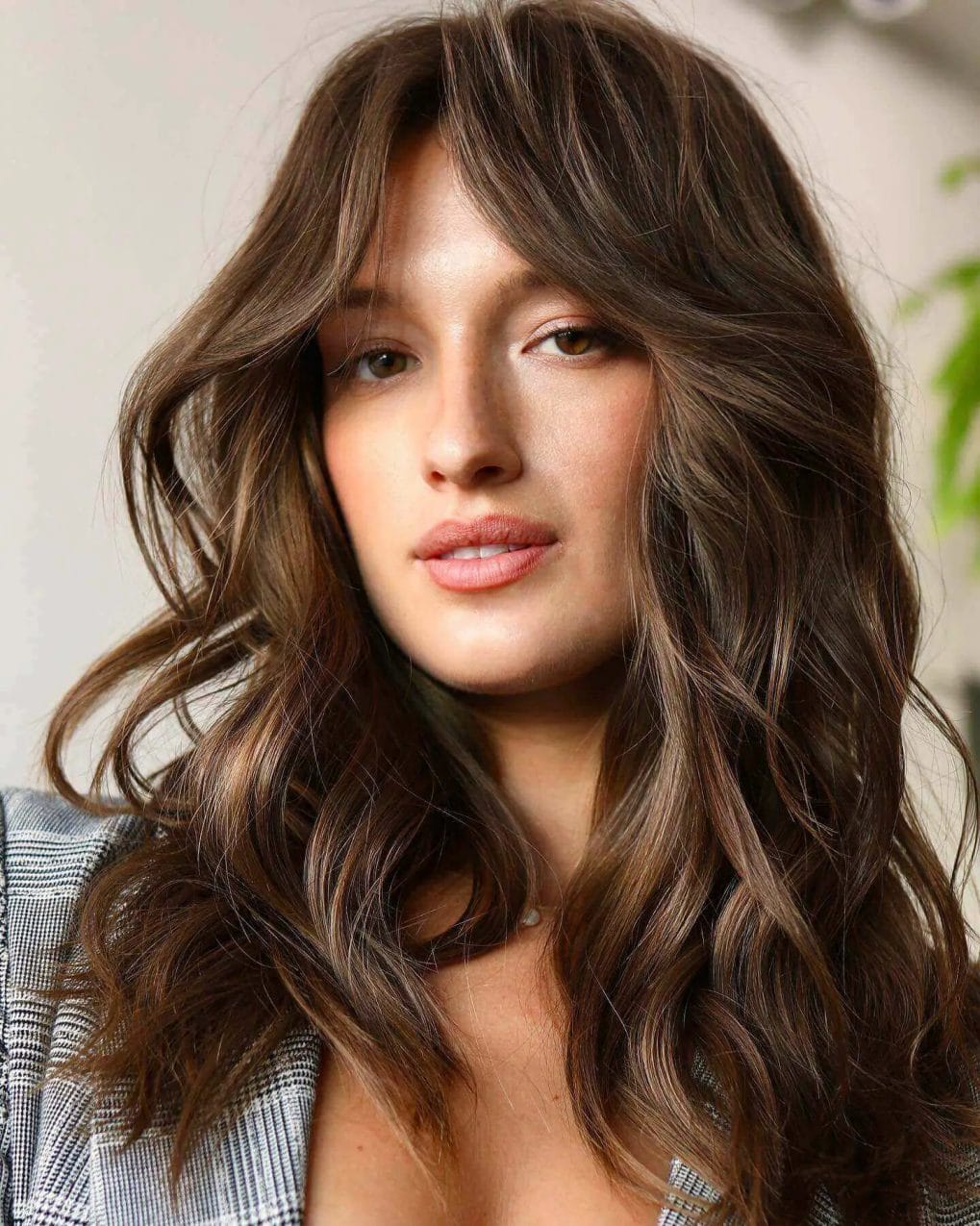 Rich medium mocha haircut with textured voluminous layers and softly parted curtain bangs.